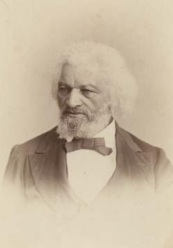 <p>Black and white photograph of a Black man with a black and white beard and white hair down to his ears facing the camera but looking to the right. 他穿着黑色西装，打着领结. </p>