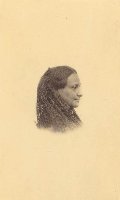 <p>A black and white photograph with a yellow tinge depicting a Black woman's face and shoulders in profile. 那个女人微笑着，她的头发编成辫子垂在肩上.</p>